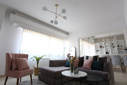 Vista amplia del living de Naza Winograd con el Esquinero Elton gris malva, el Sillón Matero Alpes rosa y el comedor de fondo