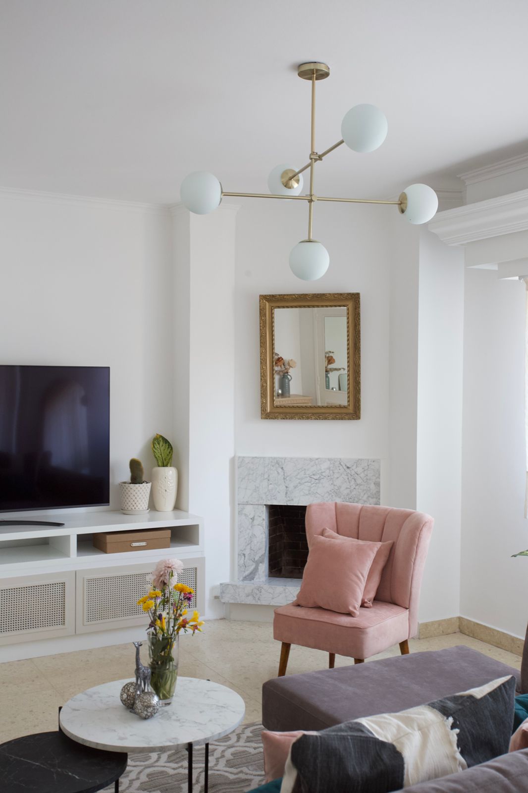 Sillón Matero Alpes rosa junto a la chimenea de mármol, con el Esquinero Elton gris malva adelante, en el living de Naza Winograd
