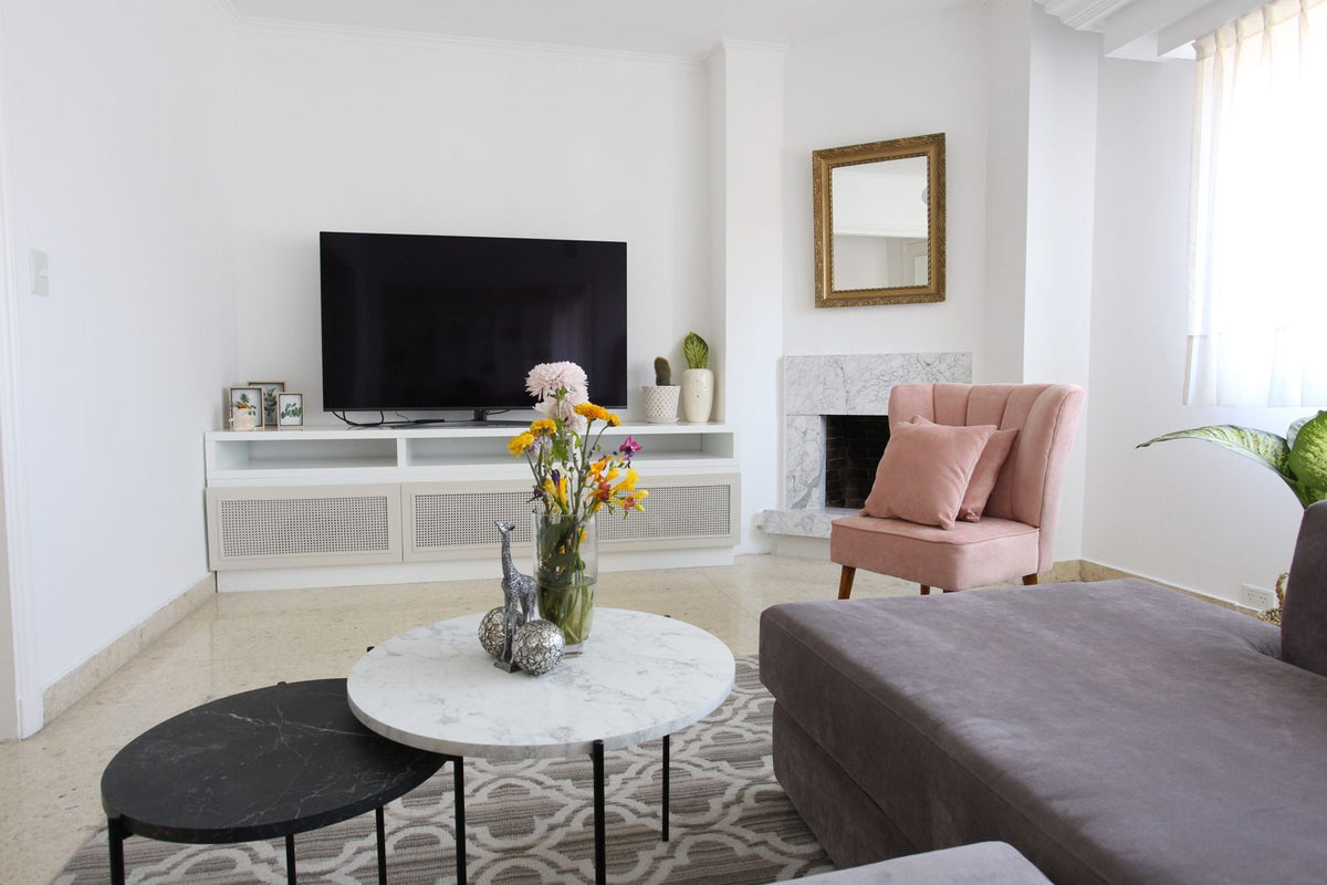 Living de Naza Winograd con mueble de TV blanco, chimenea, Sillón Matero Alpes rosa y Esquinero Elton gris malva