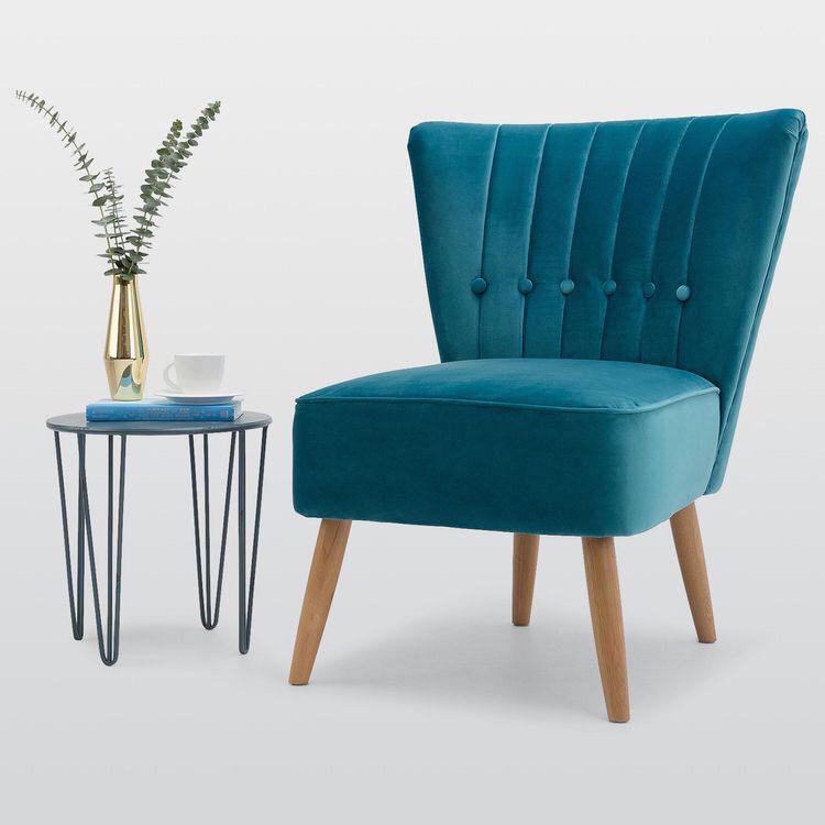 Sillón Matero Virgilio azul petróleo junto a una mesa auxiliar de hierro