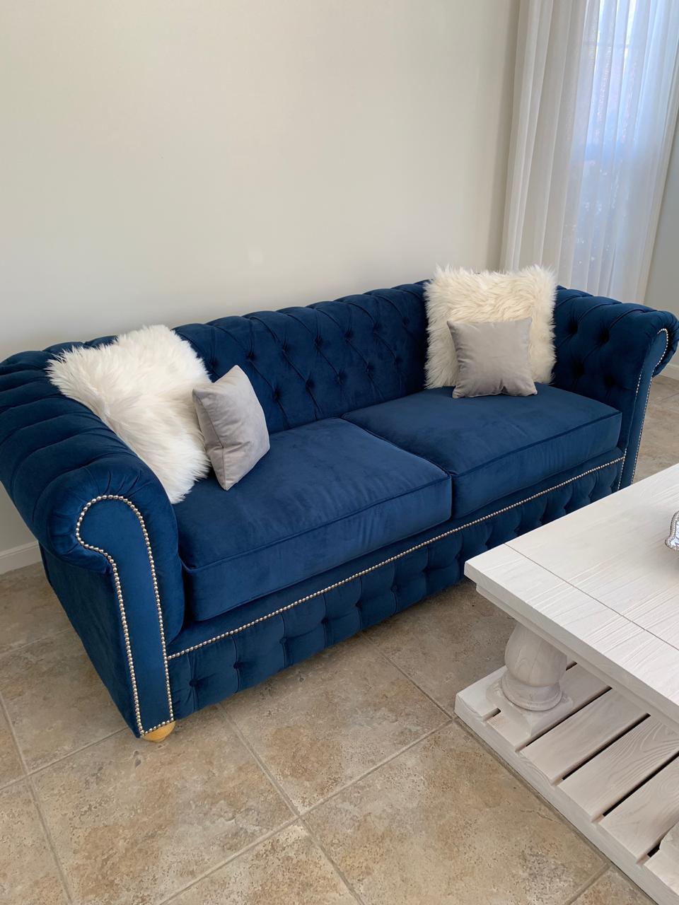 Sofá Chesterfield azul marino de dos cuerpos, vista completa con patas de madera clara