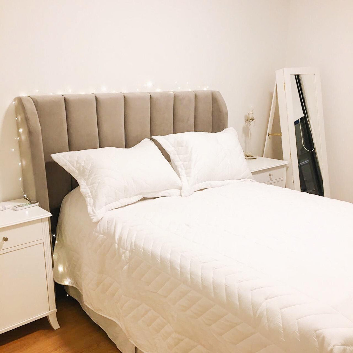 Cama completa con el Respaldo Alpes gris, mesa de luz y espejo, en el dormitorio de Martha