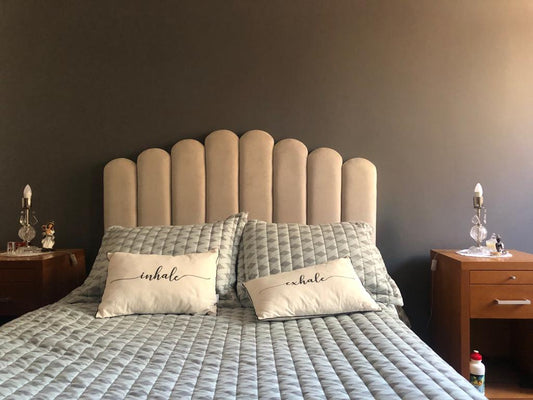 Respaldo de Cama Angie nude de paneles redondeados entre dos mesas de luz de madera, en el dormitorio de Sandra, con almohadones inhale y exhale