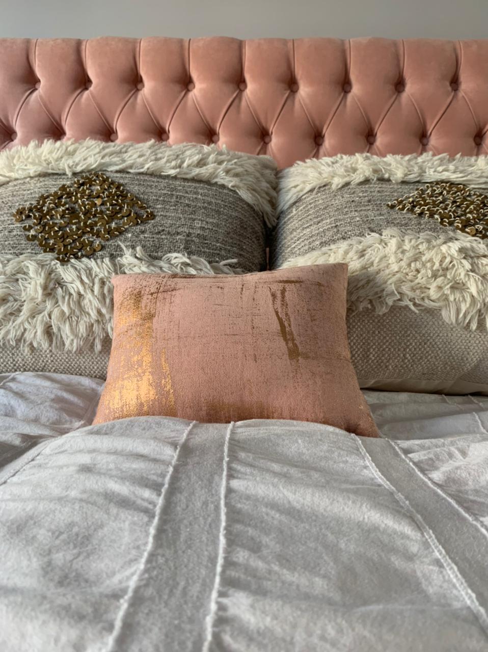 Detalle del capitoné del Respaldo Emmy rosa detrás de almohadones de pelo y dorados