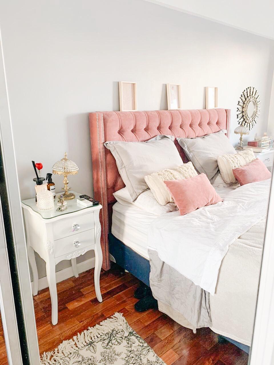 Respaldo Emmy en pana rosa con capitoné y orejas, junto a una mesita de luz blanca, en el dormitorio de Lilian