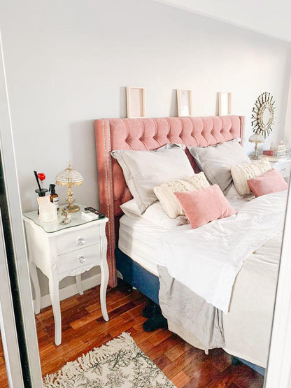Respaldo Emmy en pana rosa con capitoné y orejas, junto a una mesita de luz blanca, en el dormitorio de Lilian