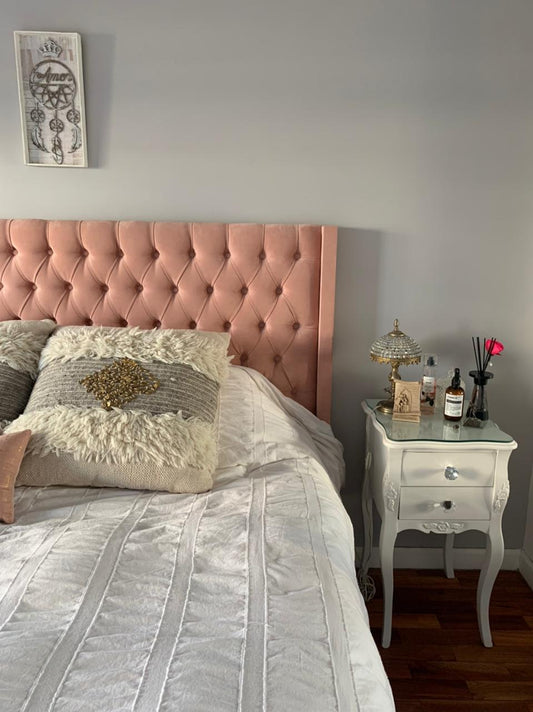 Respaldo alto tapizado en terciopelo rosa suave con diseño capitoné de botones, que aporta un toque elegante y acogedor al dormitorio