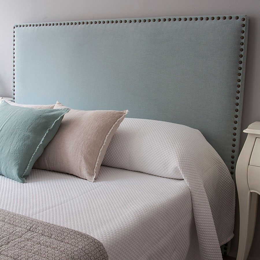 Respaldo de cama Molly tapizado en tela lisa con contorno decorado por una línea de tachas metálicas, diseño elegante y moderno para dormitorios con estilo.