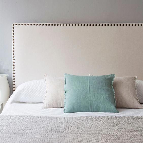 Respaldo de cama Molly tapizado en tela lisa con contorno decorado por una línea de tachas metálicas, diseño elegante y moderno para dormitorios con estilo.