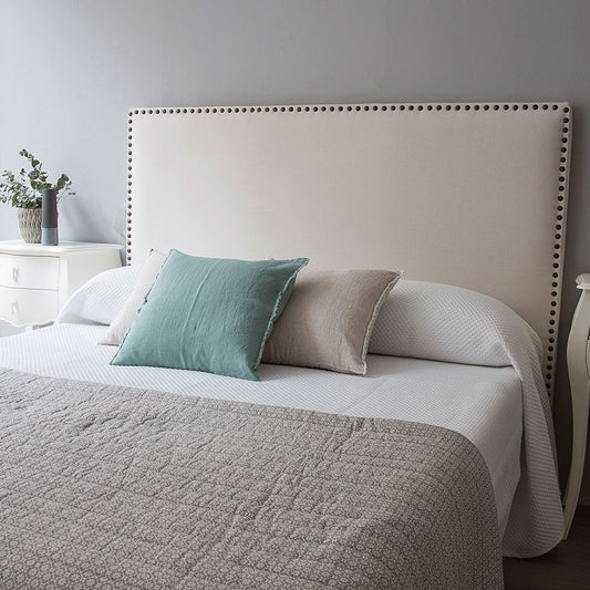 Respaldo de cama Molly tapizado en tela lisa con contorno decorado por una línea de tachas metálicas, diseño elegante y moderno para dormitorios con estilo.