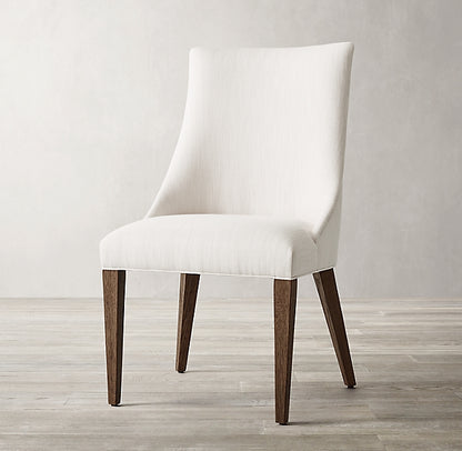 Silla Amalfi en crema de frente, con respaldo curvo envolvente y patas de madera