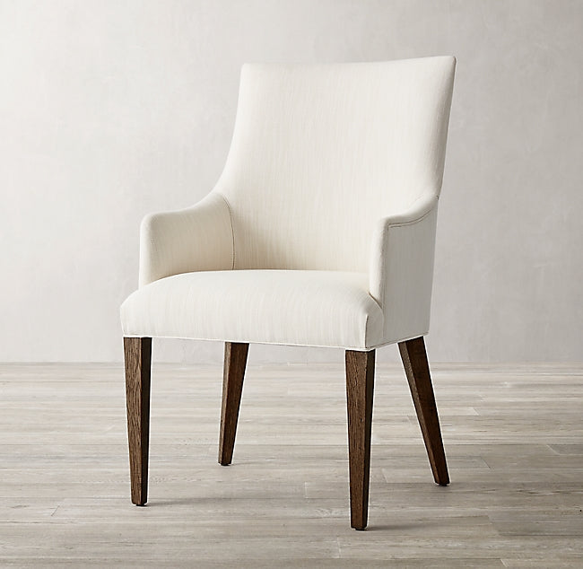 Silla Amelia en crema de frente, con apoyabrazos inclinados y patas de madera oscura