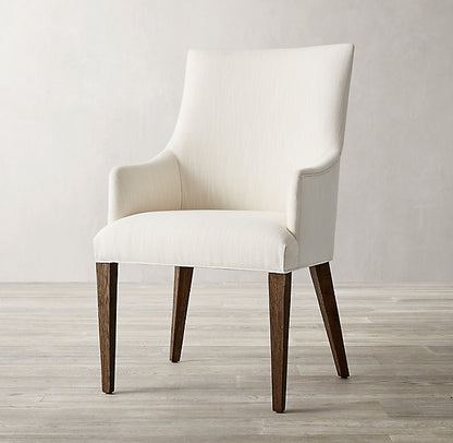 Silla Amelia en crema de frente, con apoyabrazos inclinados y patas de madera oscura