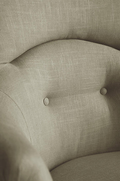 Sillón individual de diseño tradicional en tono gris, con respaldo curvo, apoyabrazos tallados y patas delanteras de madera con ruedas.