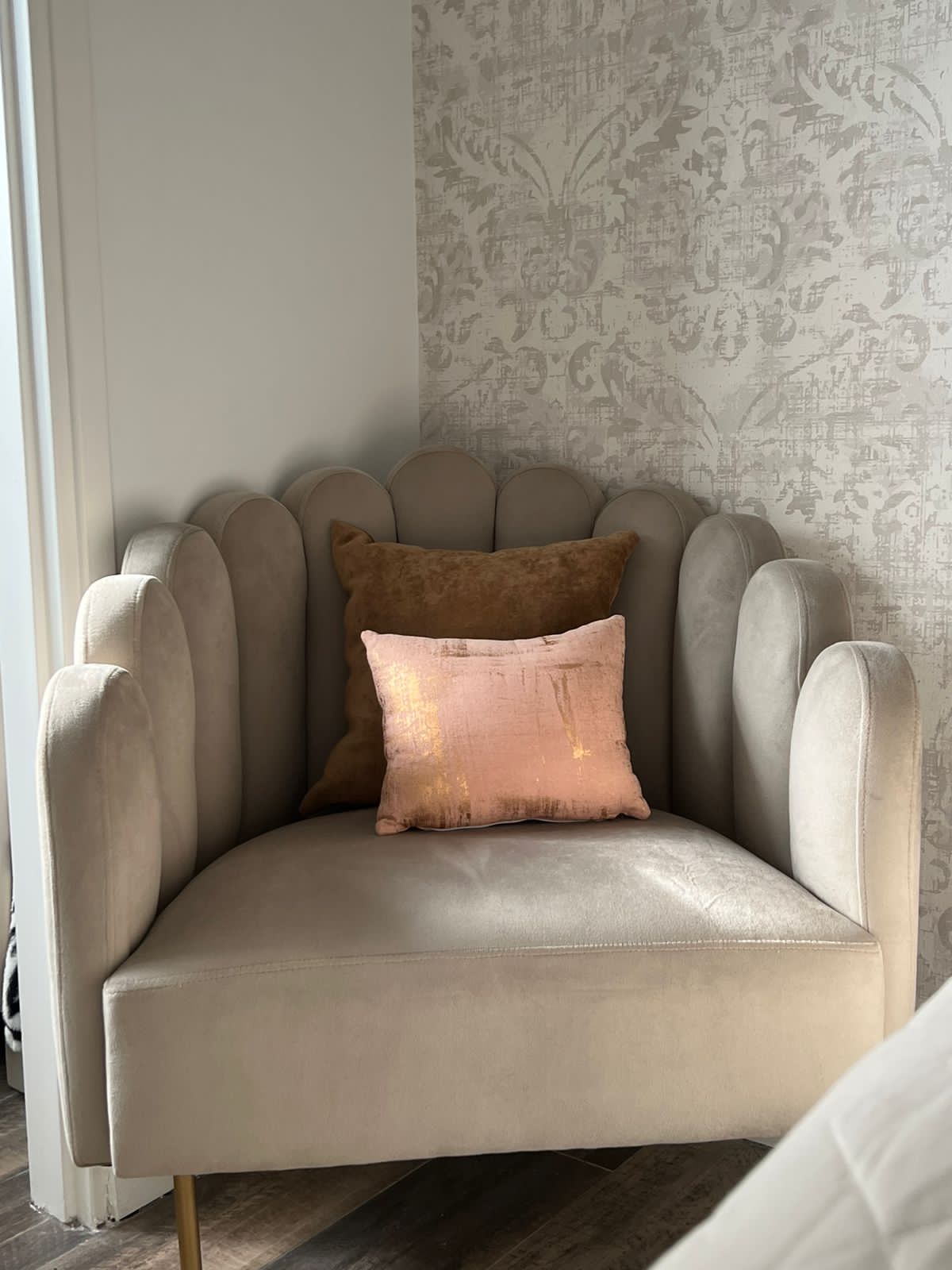 Detalle del Sillón Angie beige, con respaldo en forma de pétalos y almohadones marrón y rosa, en la casa de Naza Winograd