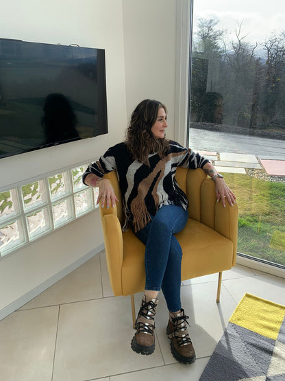 Una mujer sentada en el Sillón Angie mostaza, junto al ventanal del loft en Ushuaia