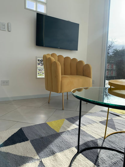 Sillón Angie mostaza junto a la mesa de vidrio y la alfombra geométrica del loft en Ushuaia