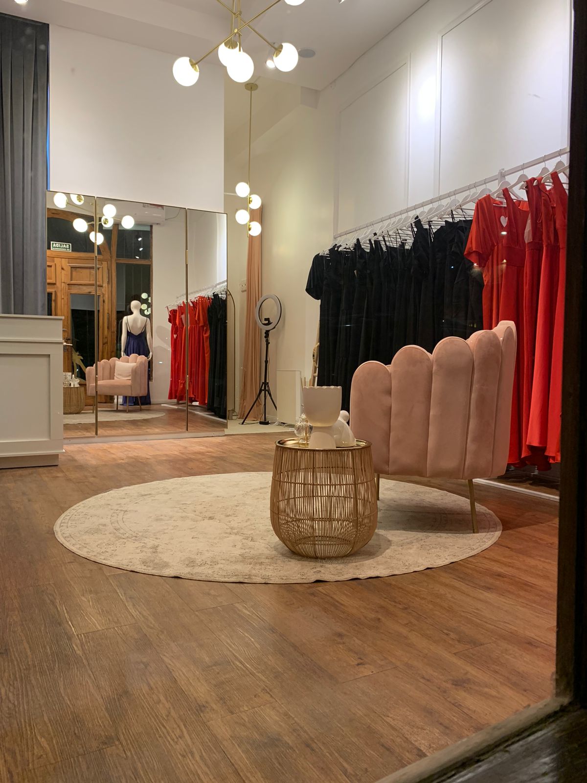 Sillón Angie rosa sobre una alfombra redonda, con mesa de apoyo dorada, en el local de Natalia Oreiro