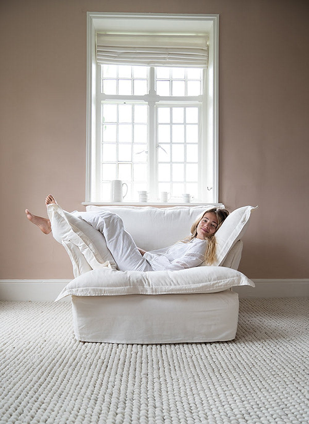 Sillón Comfy de un cuerpo en blanco con almohadones sueltos, en el rincón de lectura de una clienta
