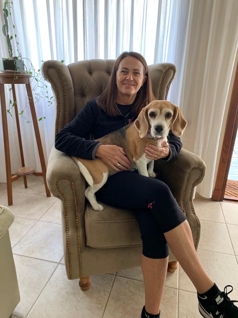 Lorena sentada con su beagle en el Sillón Elepant color topo, con orejas, capitoné y tachas, en su casa de Balcarce