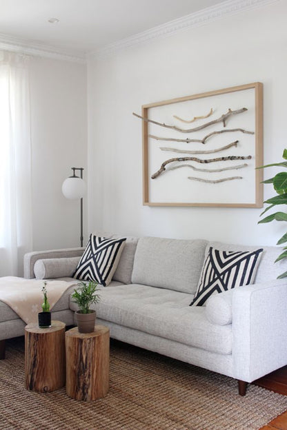 Sillón esquinero Bambú en tono claro con almohadones a rayas, junto a una mesa de troncos