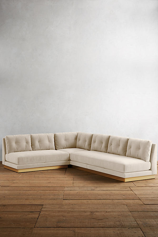Sillón esquinero Cardiff en crema con base de madera a la vista, en un espacio minimalista