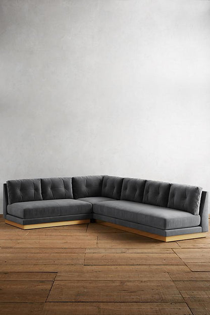 Sillón esquinero Cardiff en gris topo con respaldo de botones y base de madera a la vista