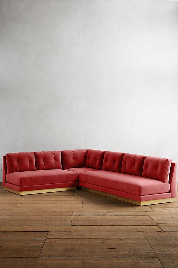 Sillón esquinero Cardiff en rojo con respaldo de botones, en un espacio minimalista