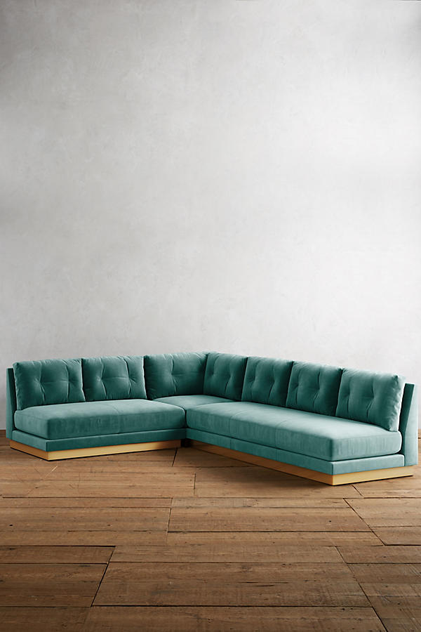 Sillón esquinero Cardiff en verde, con mesa ratona redonda y butaca blanca frente al ventanal