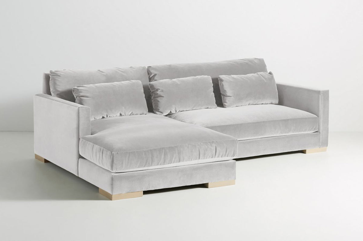 Sillón esquinero Steven en gris claro con patas de madera, vista en diagonal sobre fondo blanco