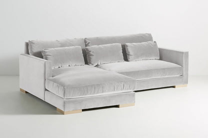 Sillón esquinero Steven en gris claro con patas de madera, vista en diagonal sobre fondo blanco