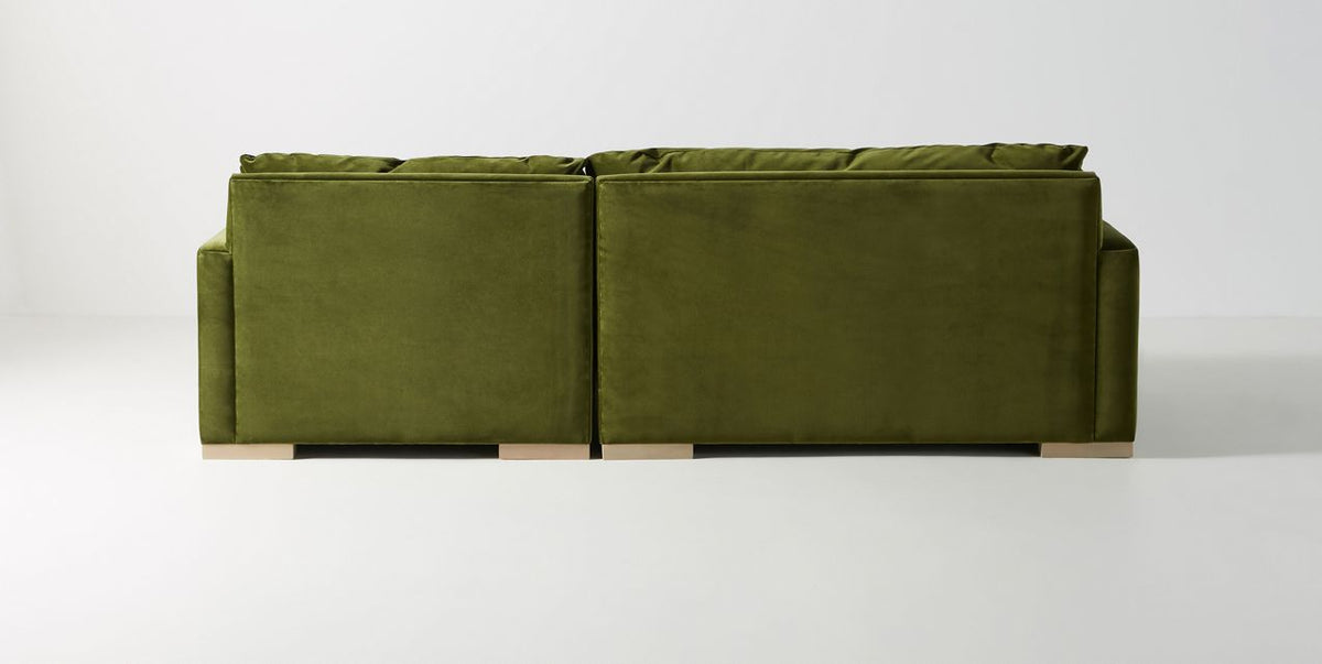 Vista de frente del Sillón esquinero Steven en verde, con chaise longue a la derecha y banco de madera