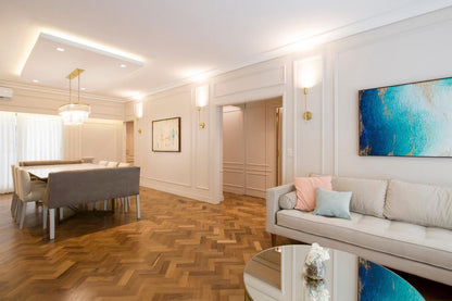 Sofá esquinero tapizado en tono beige claro, con almohadones a juego, ubicado en un living luminoso de estilo moderno.