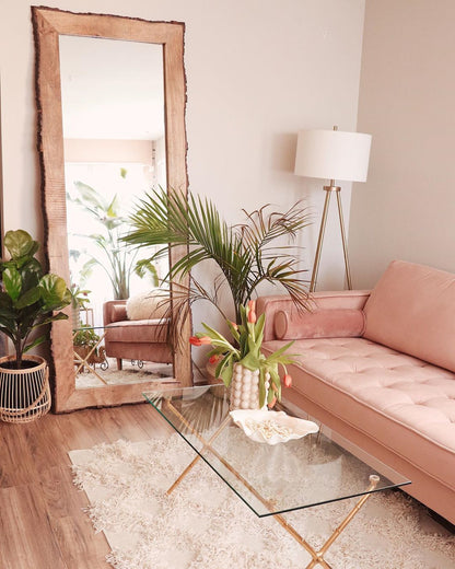 Sofá Bambú rosa con botoné en el asiento, junto a un espejo de pie y plantas en un living luminoso - Tienda de Banquitos