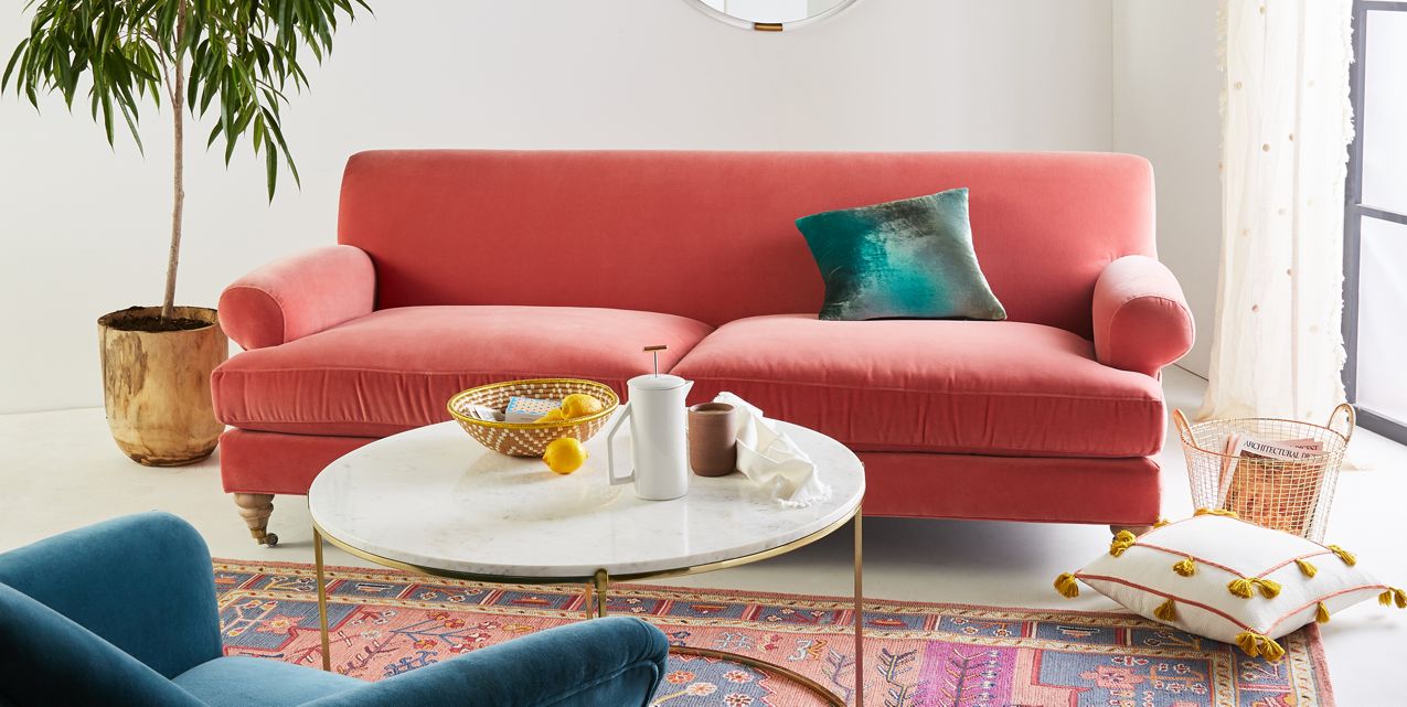Sofá Cecily tapizado en velvet coral, ambientado en living luminoso con planta y mesa ratona - Tienda de Banquitos