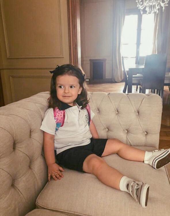 Nena sentada en el Sofá Deconstructed beige, con el capitoné del respaldo a la vista, en Belgrano